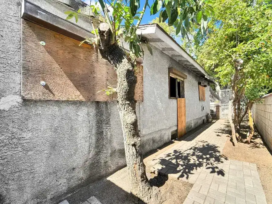 Boarded-up stucco house exterior before purchase by Drive Thru Offers